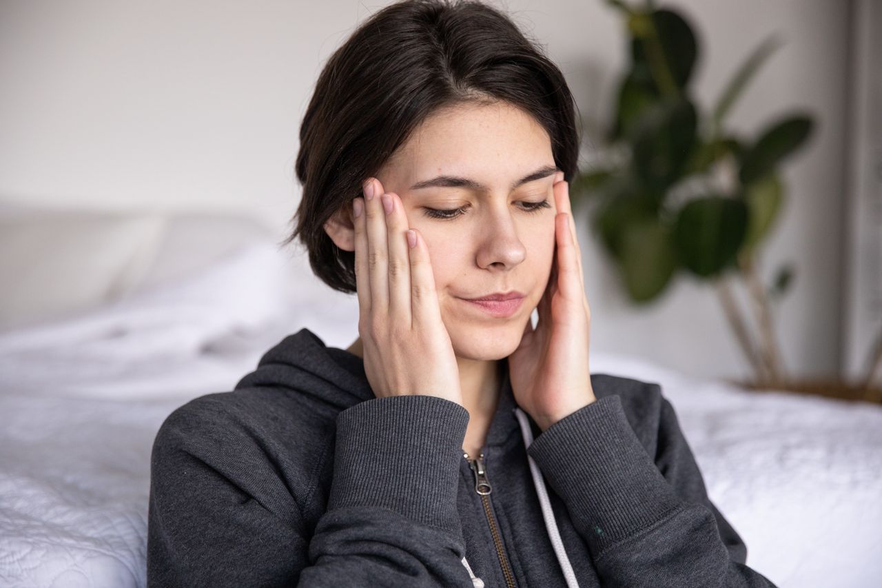 Thoughtful woman with short hair in a hoodie sitting pensively indoors, reflecting quietly.